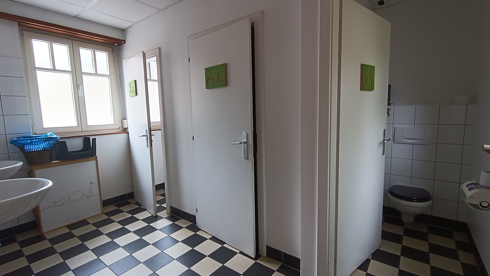 petite salle avec lavabo et donnant accès à trois toilettes fermés
