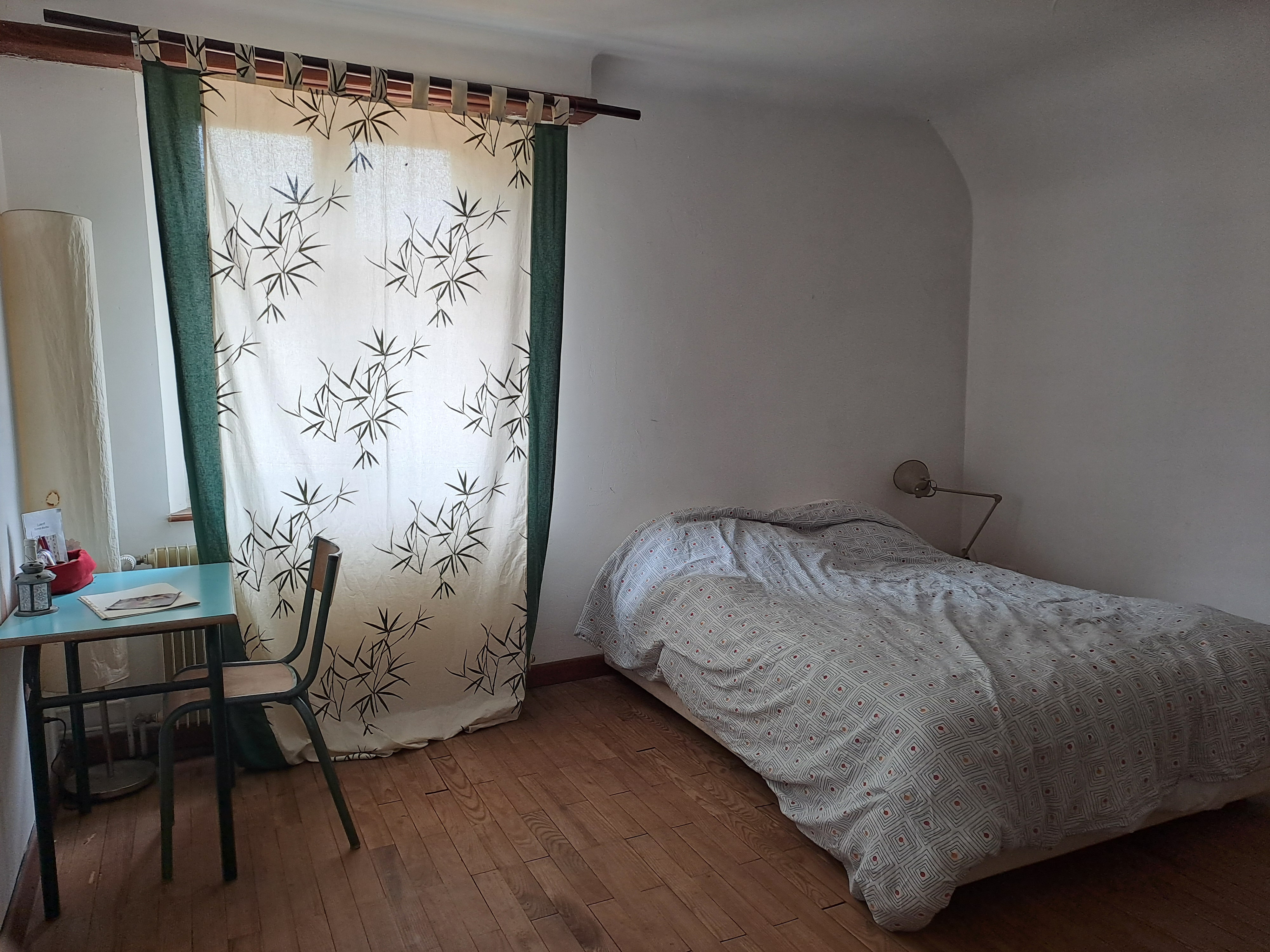 une chambre avec un lit double du parquet et une table de nuit et une table avec chaise