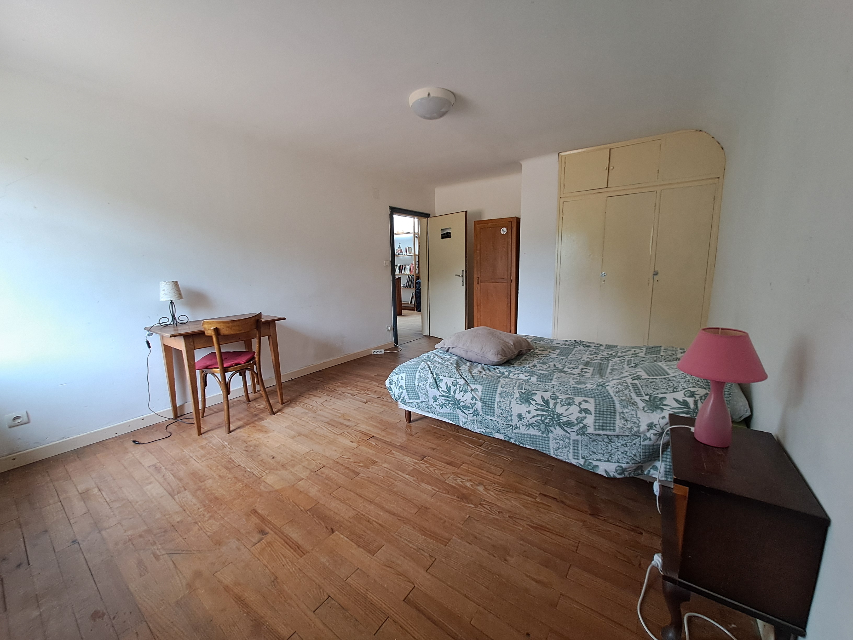 une chambre avec un lit double du parquet et une table de nuit et une table avec chaise