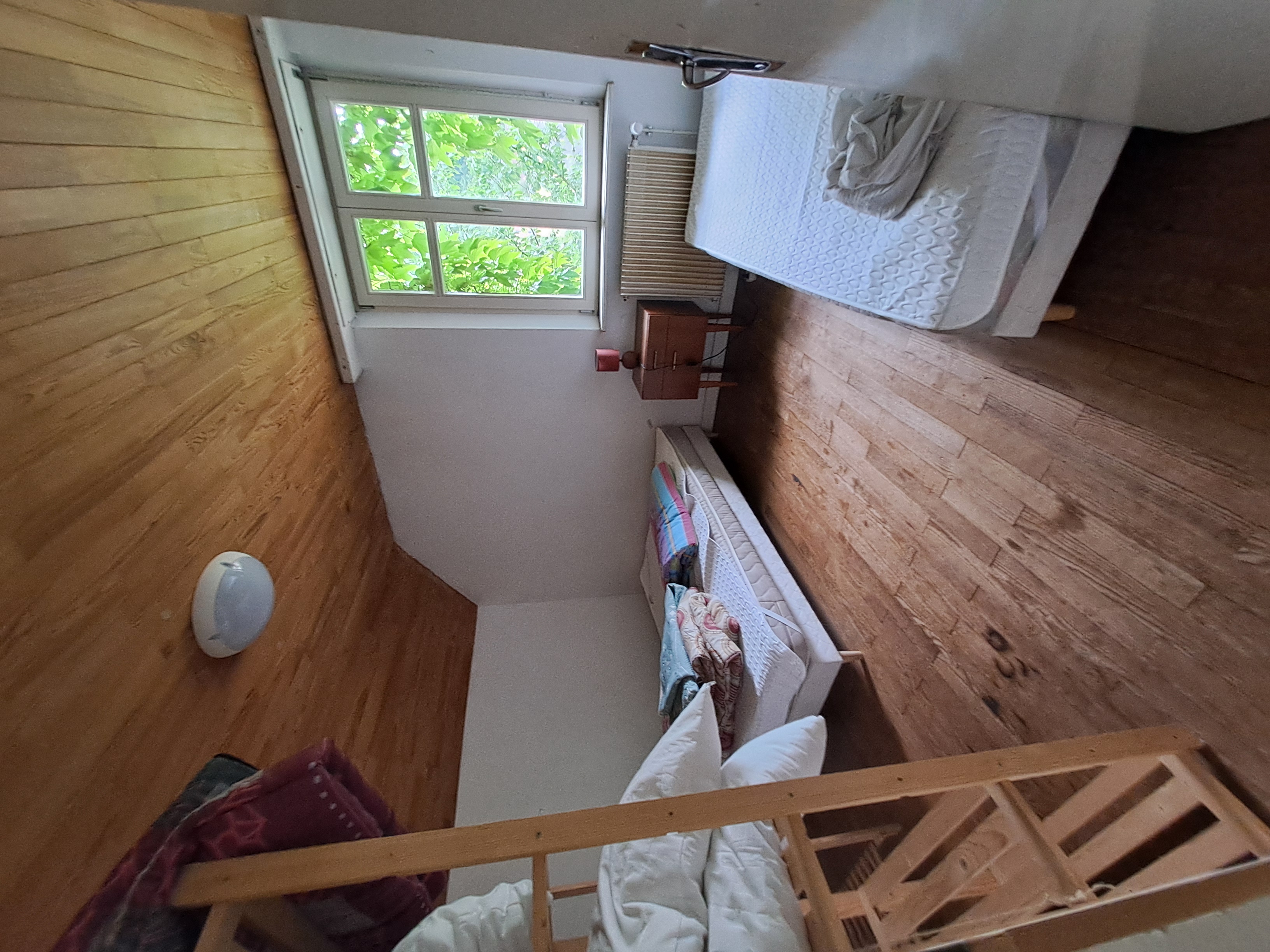 une chambre avec deux lits simples du parquet du lambris au plafond et une fenetre