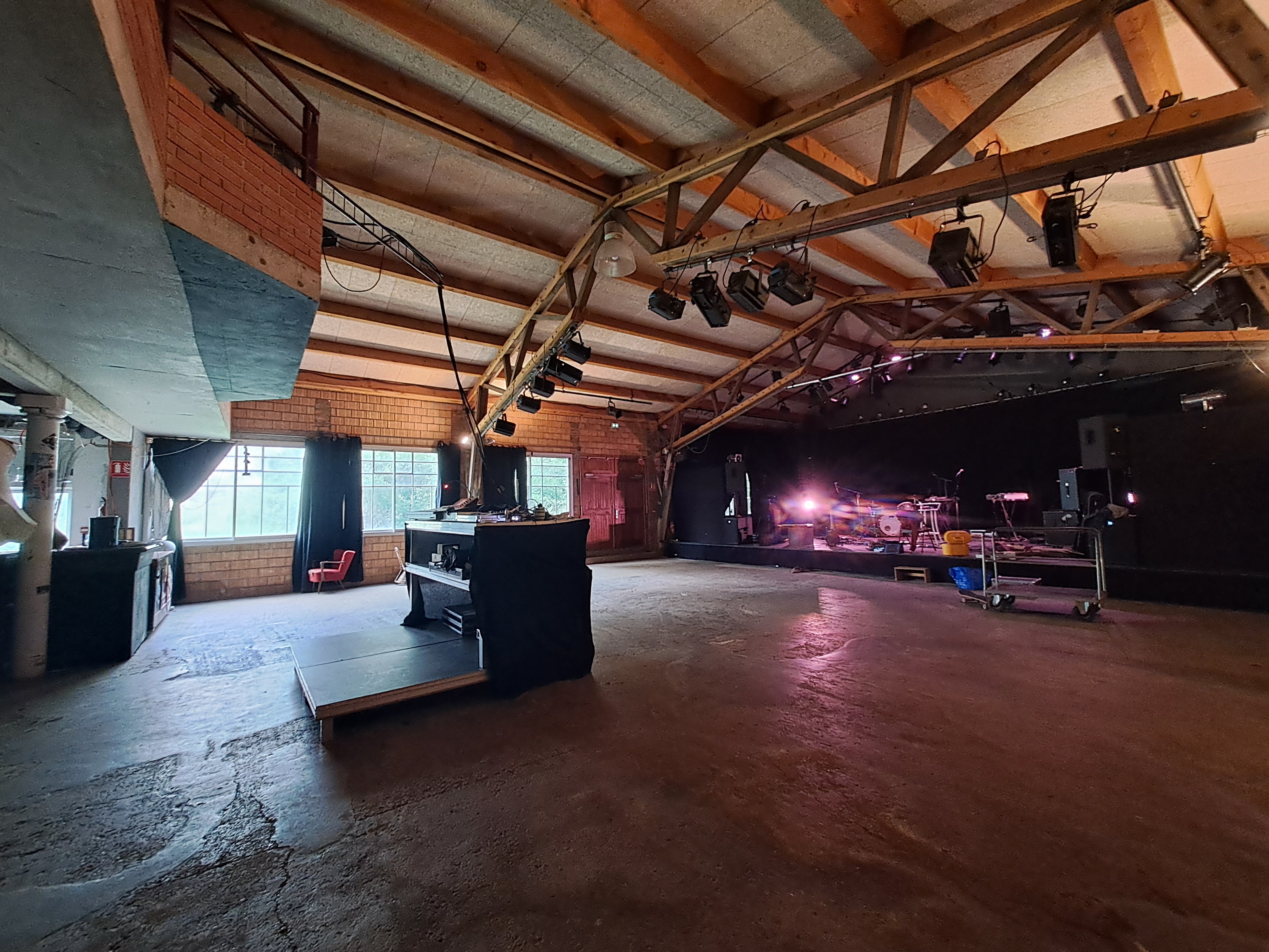 salle de spectable où l'on voit la scène la régie son et lumière et la charpente avec un balcon en premier étage face à la scène