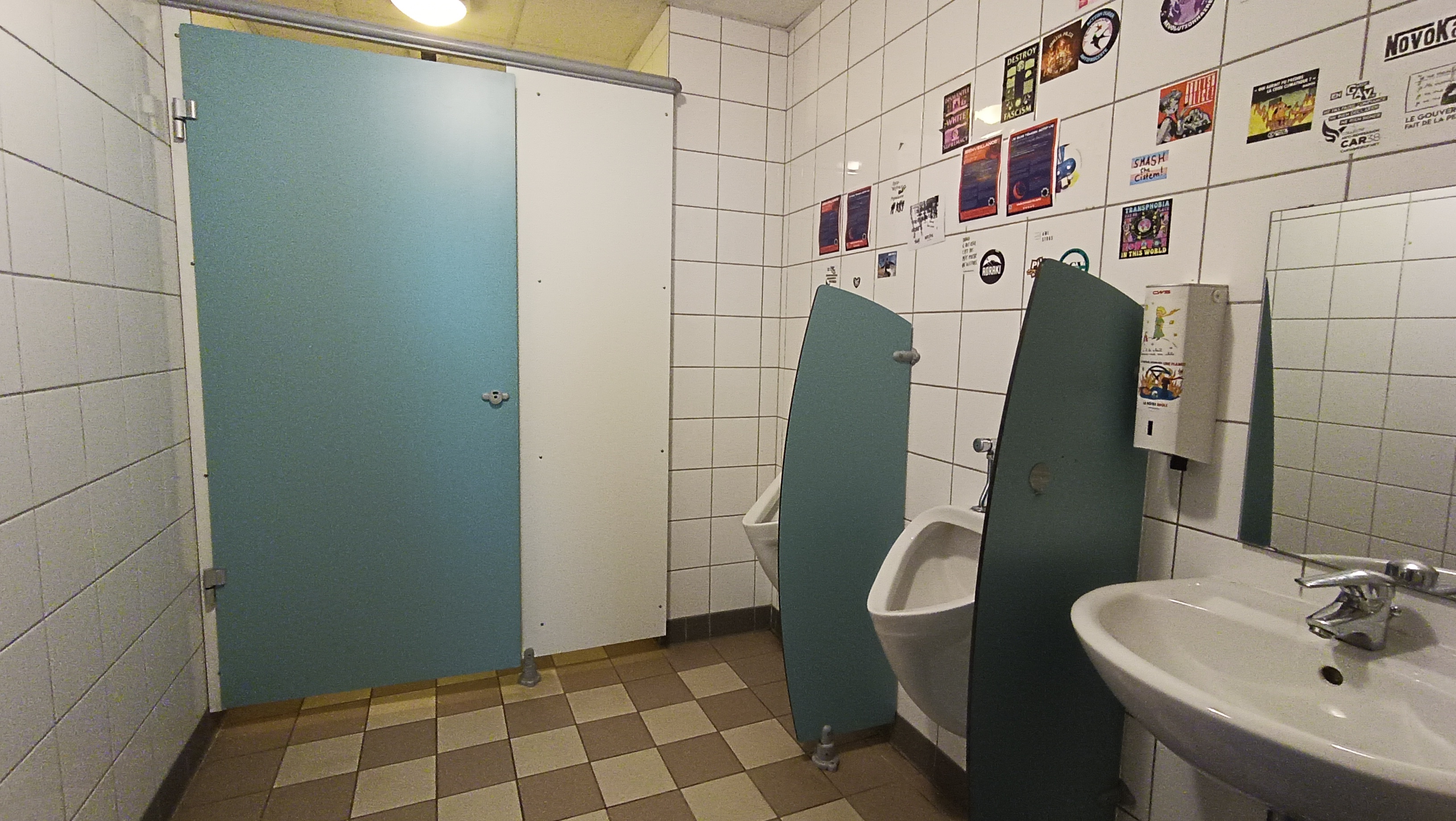 toilettes avec lavabo et urinoirs et une porte fermée donnant sur un cabinet assis